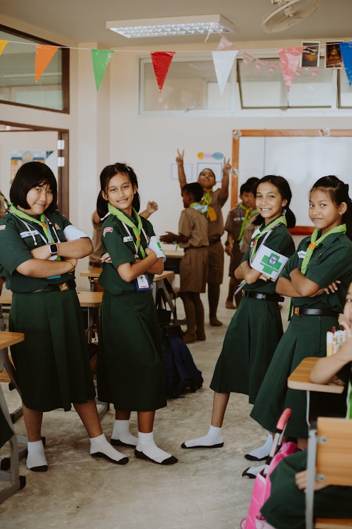 A diverse group of students in green uniforms pose confidently in a classroom.