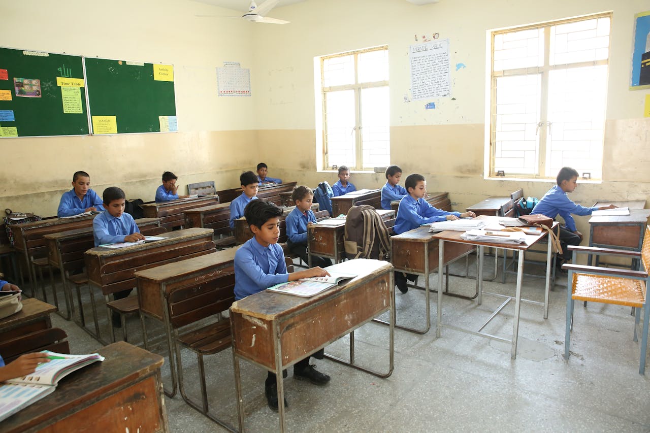 A group of young boys studying in a bright classroom filled with educational posters.