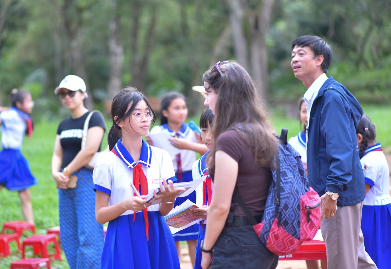 Group of schoolchildren in uniform engaging with teachers outdoors, fostering learning.