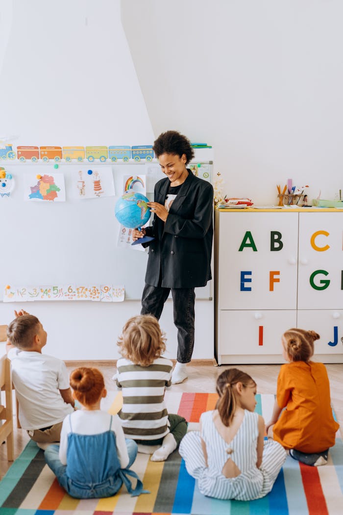 A teacher engaging preschool children with a globe in a classroom setting.